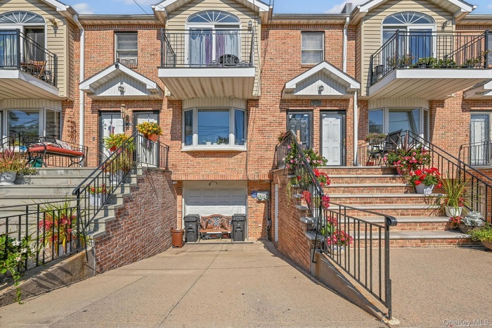 View of front of house featuring brick siding, driveway, a balcony, and an attached garage