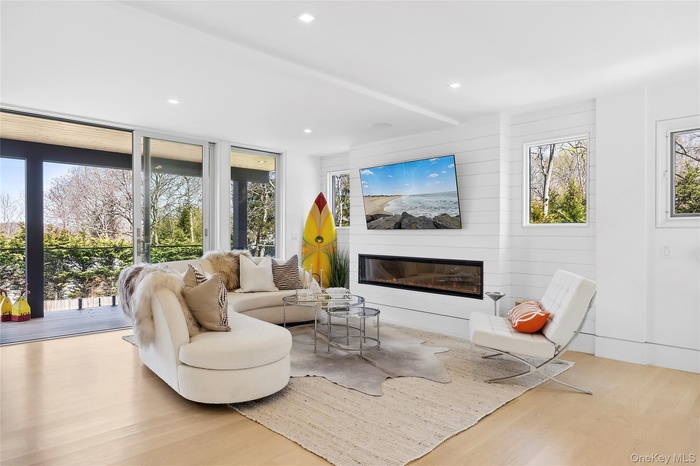 Living area with a glass covered fireplace, wood finished floors, and recessed lighting