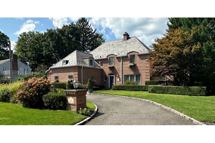 French country style house featuring a high end roof, a front yard, brick siding, and a chimney