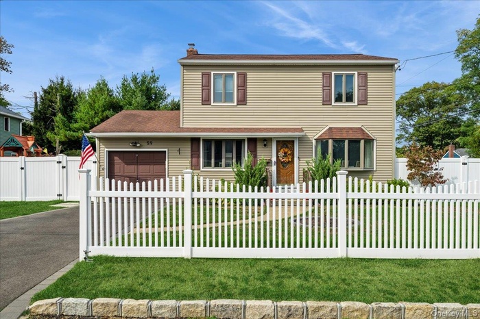 Traditional-style home with an attached garage, a fenced front yard, driveway, and a gate