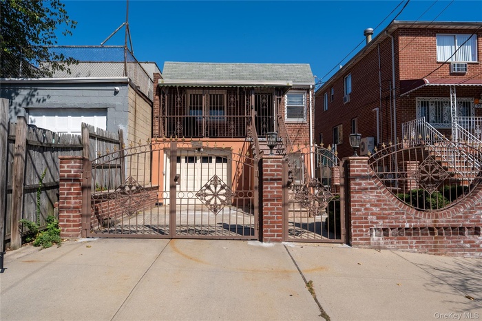 View of front of home with a gate, a fenced front yard, driveway, brick siding, and roof with shingles