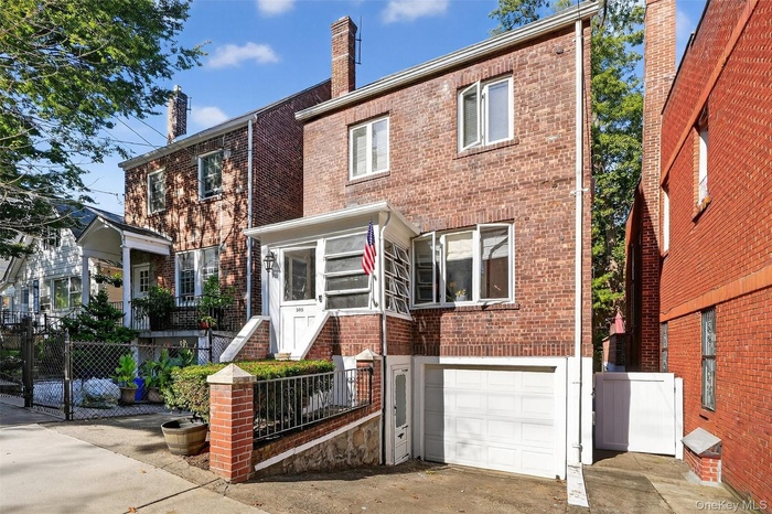 Traditional-style home with brick siding, a gate, an attached garage, and driveway