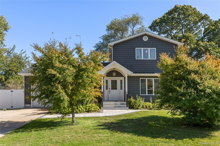 View of front of property featuring a front yard, concrete driveway, and a garage