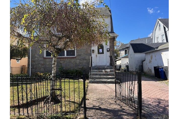 View of front facade featuring a fenced front yard, stone siding, and a gate