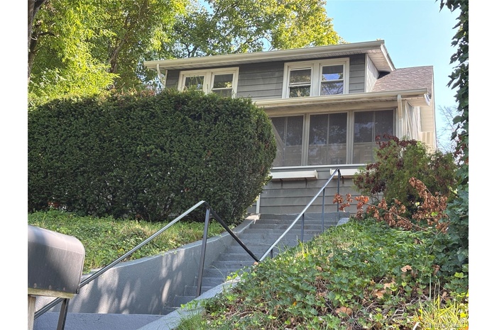 View of front facade featuring stairs and a sunroom