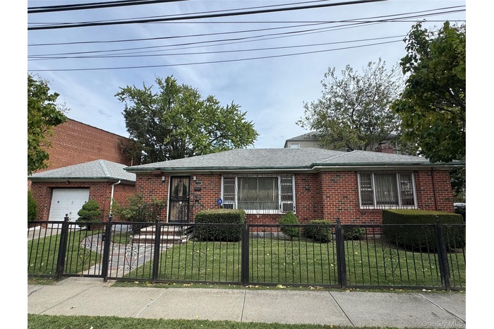 Ranch-style home with a fenced front yard, brick siding, an attached garage, and a chimney