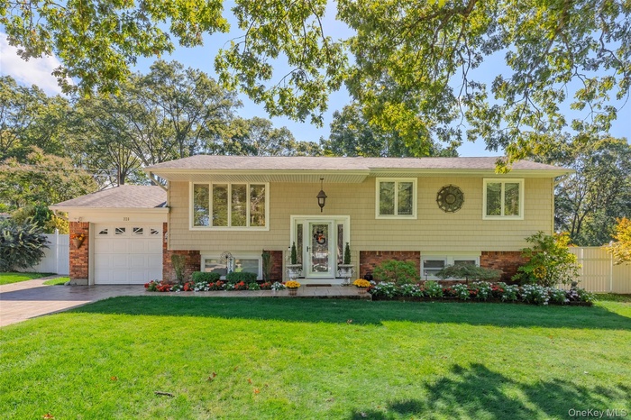 Bi-level home featuring brick siding, an attached garage, driveway, and a shingled roof