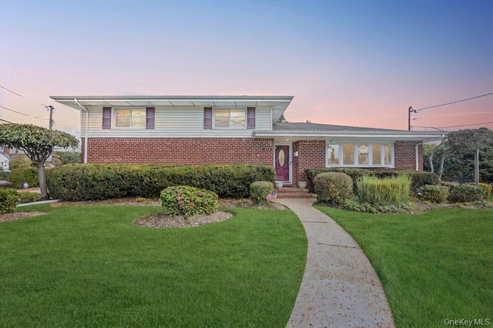 Tri-level home featuring a front lawn and brick siding
