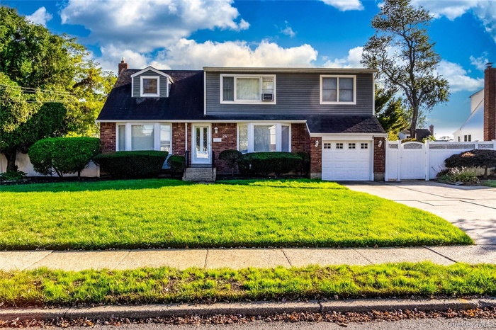 View of front facade featuring brick siding, driveway, an attached garage, a chimney, and roof with shingles