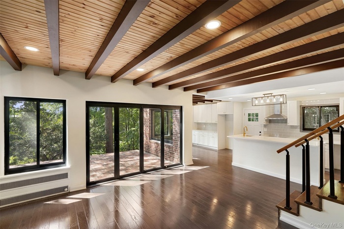 Unfurnished living room with radiator, dark wood-style flooring, stairway, recessed lighting, and a wood ceiling with exposed beams