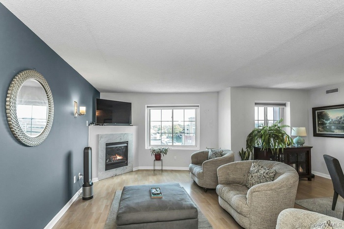 Living area featuring a high end fireplace, healthy amount of natural light, wood finished floors, and a textured ceiling