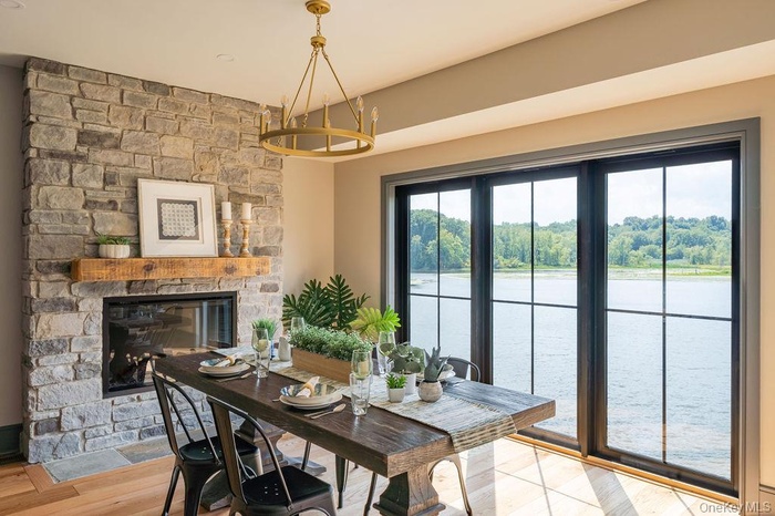 Dining area featuring a stone fireplace, a water view, and light wood-type flooring