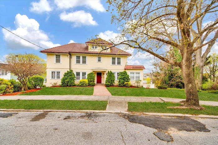 View of front of property featuring a tile roof, a front lawn, and stucco siding