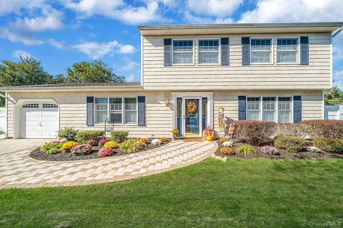 Colonial house with a front yard, an attached garage, and concrete driveway