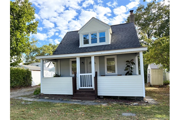 Bungalow-style house with roof with shingles, covered porch, a chimney, and a storage shed