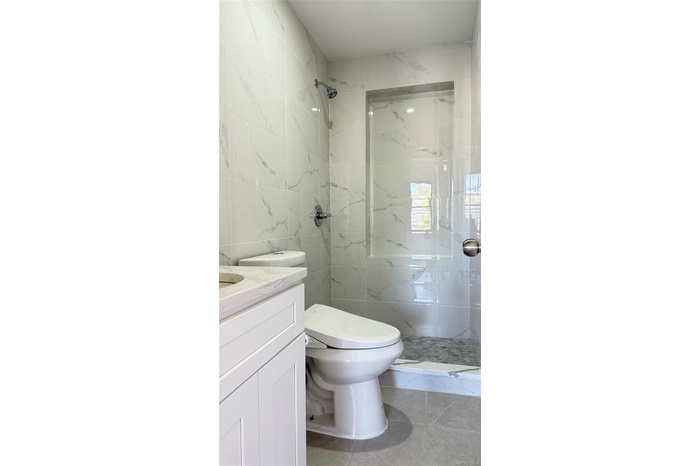 Full bathroom featuring vanity, tile walls, and a marble finish shower