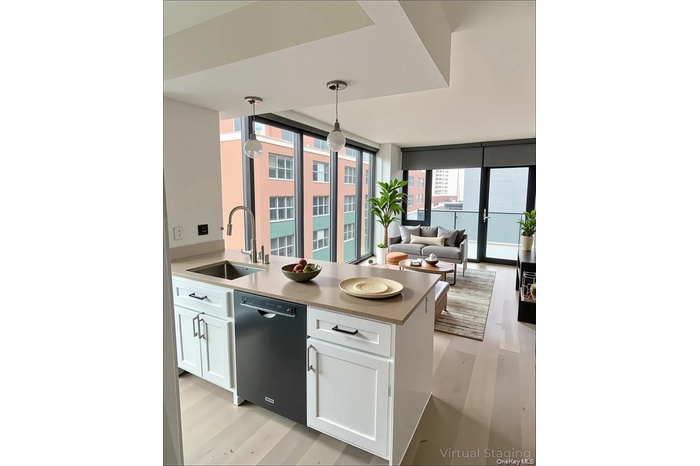 Kitchen with light wood-type flooring, pendant lighting, white cabinets, and black dishwasher