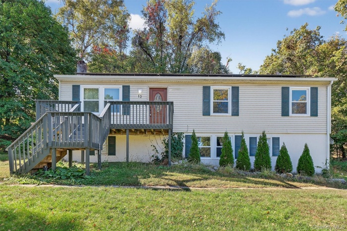 View of front of property featuring a wooden deck, a front lawn, stairway, and a chimney