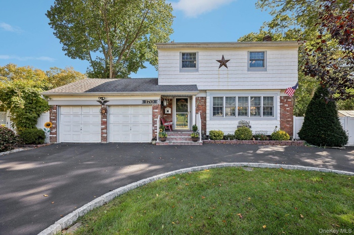 Colonial featuring a circular driveway, 2 car garage, and an inviting front porch.