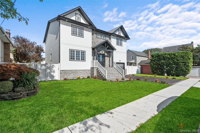 View of front facade with stone siding and driveway