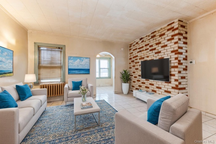 Living room featuring tile patterned flooring, radiator, and arched walkways