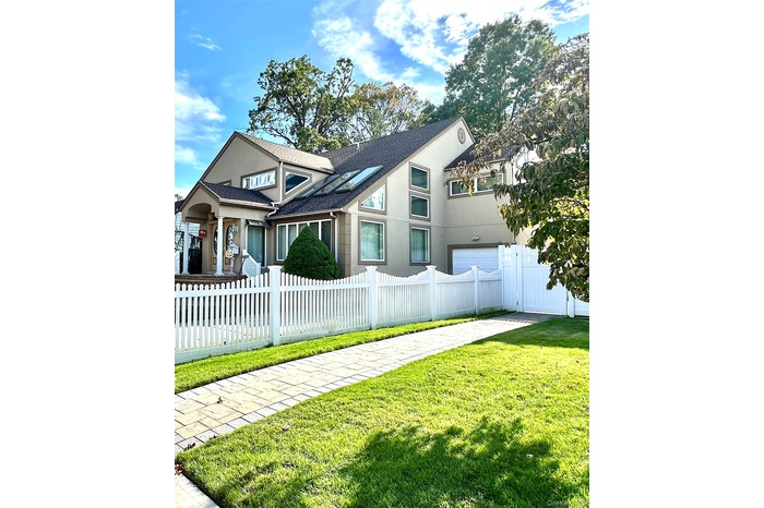 View of front facade with a shingled roof, stucco siding, and a fenced front yard