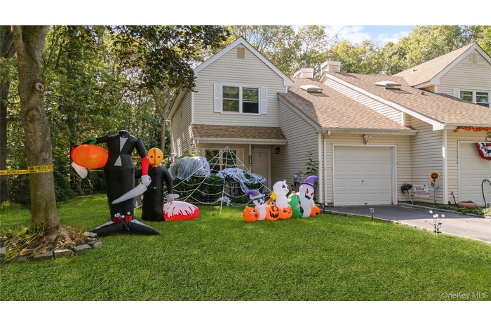 Traditional home featuring driveway, a front yard, an attached garage, and roof with shingles