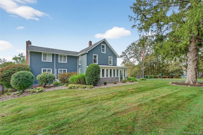 Rear view of house featuring a chimney, a lawn, a playground, and a sunroom