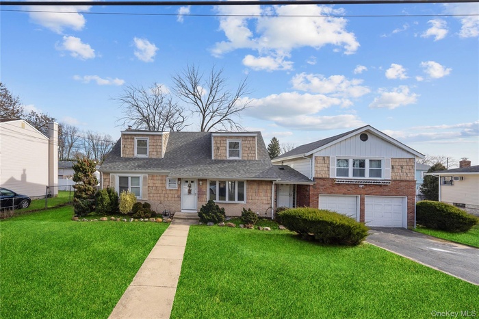 View of front of house featuring a front yard, roof with shingles, driveway, an attached garage, and brick siding