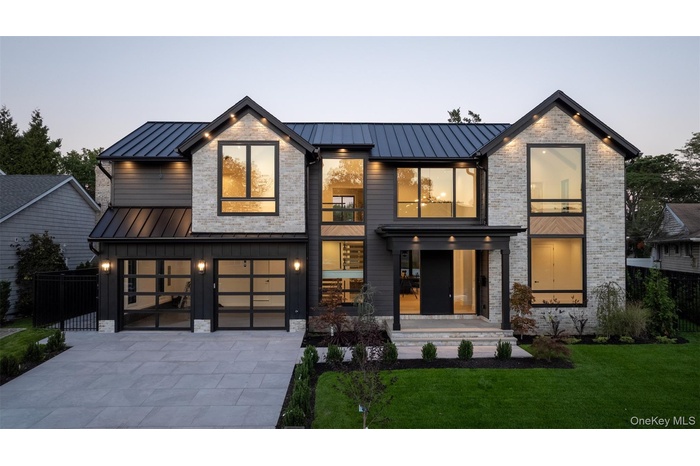 Contemporary house with a standing seam roof, a metal roof, an attached garage, concrete driveway, and brick siding