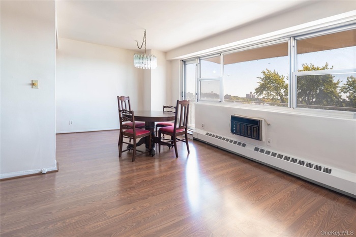 Dining space featuring baseboard heating, dark wood-style floors, and a chandelier