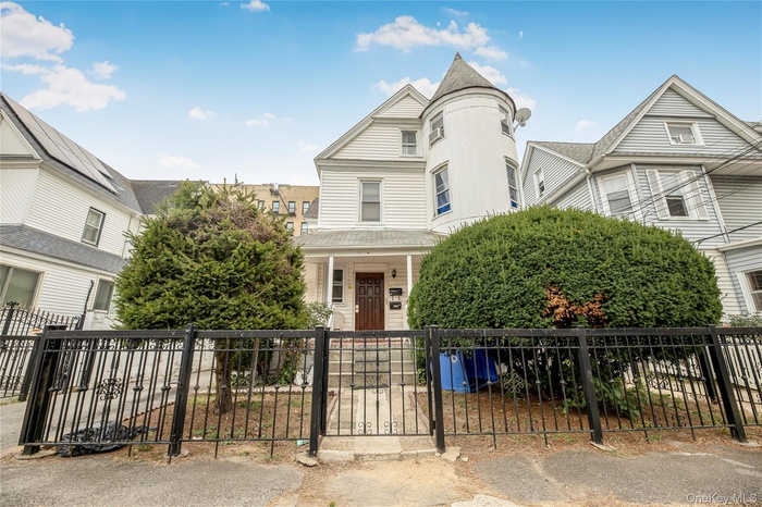 Victorian-style house with a fenced front yard, a gate, and a porch