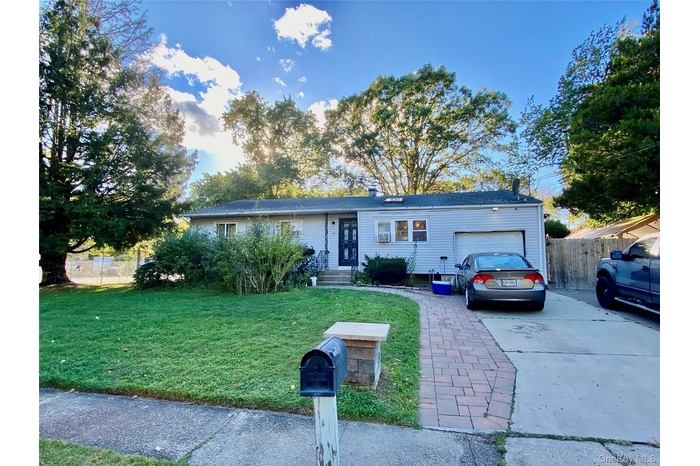 Ranch-style home featuring concrete driveway, an attached garage, and a chimney