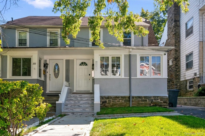 American foursquare style home with stucco siding and roof with shingles