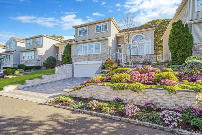 View of front of home with decorative driveway, stone siding, and a garage