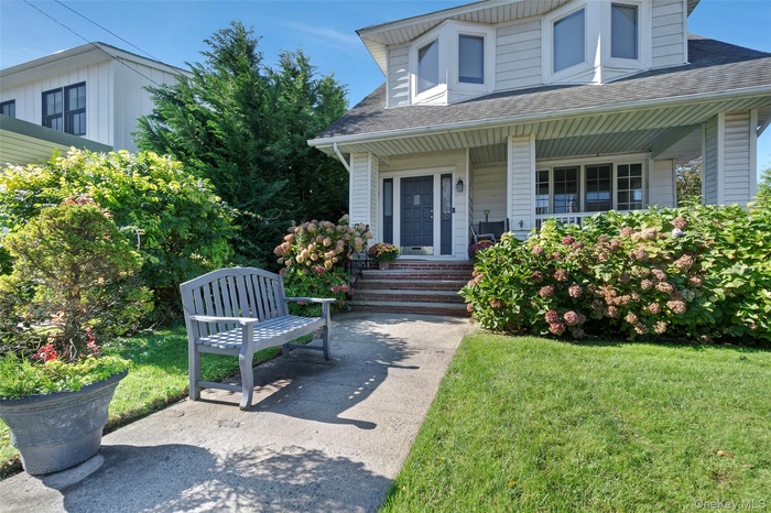 Doorway to property featuring a porch, a shingled roof, and a yard