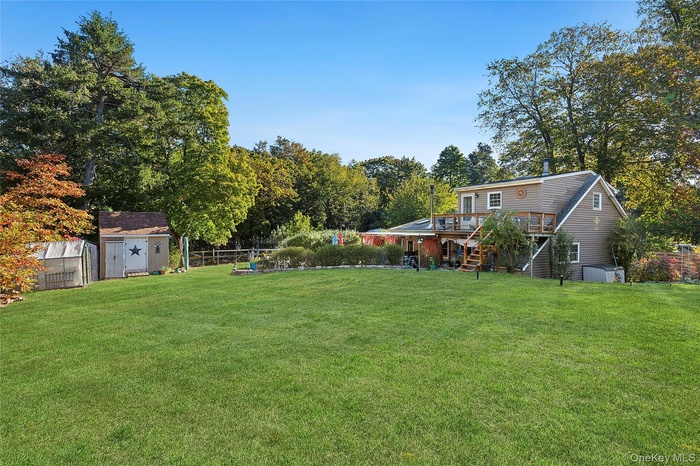 Fenced backyard with stairs, a deck, a shed, and view of wooded area