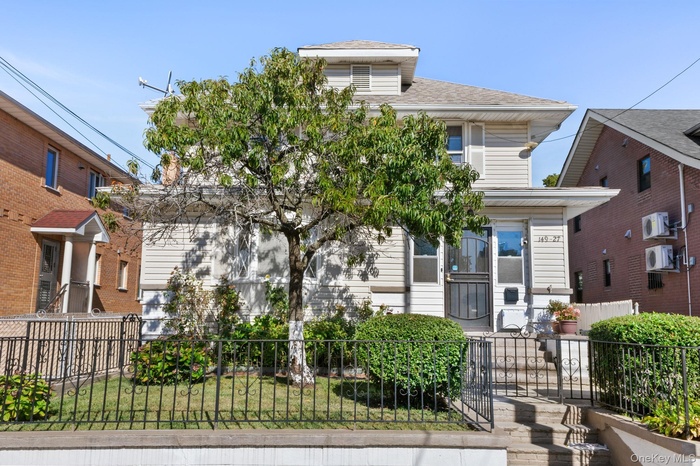 American foursquare style home with a fenced front yard and a shingled roof