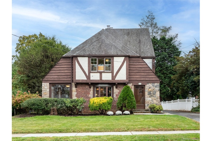 View of front facade featuring a shingled roof, stucco siding, brick siding, and a chimney
