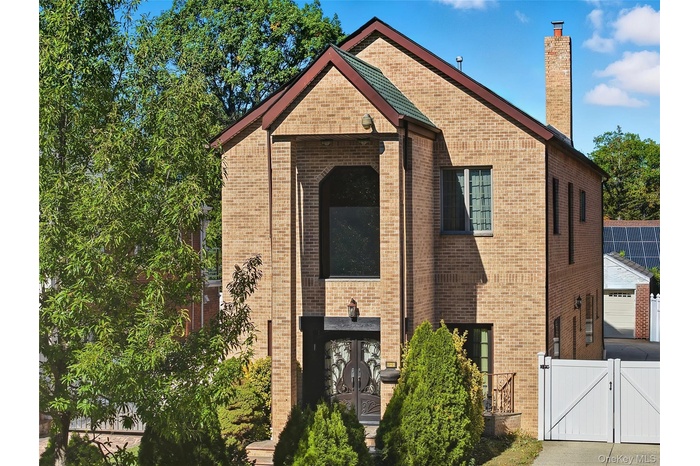 View of front of house featuring a gate, a chimney, and brick siding