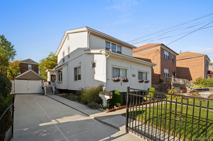 View of front of house with a detached garage and a gate