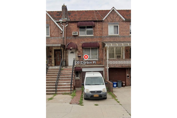 Traditional-style home with concrete driveway, brick siding, mansard roof, and an attached garage