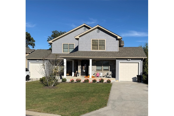 View of front of home featuring a garage, covered porch, a shingled roof, a front lawn, and driveway
