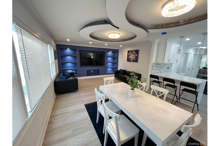Dining room featuring ornamental molding, light wood-type flooring, recessed lighting, and a raised ceiling