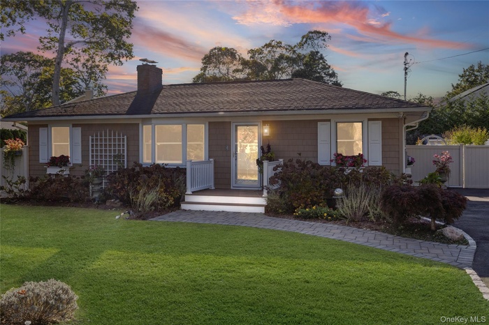 View of front of home featuring a chimney, a wooden deck, and a shingled roof