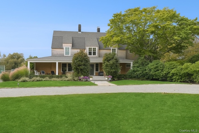 View of front of property with a porch, a front yard, and a chimney