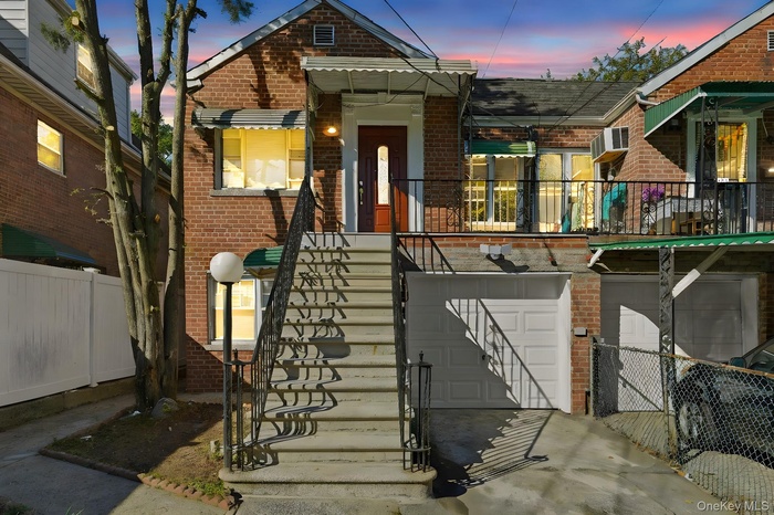 Exterior entry at dusk featuring brick siding, an attached garage, and concrete driveway