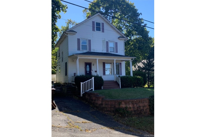 American foursquare style home featuring covered porch and a front yard