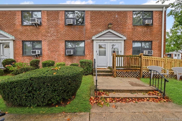 Colonial house with brick siding, a deck, cooling unit, and a front yard