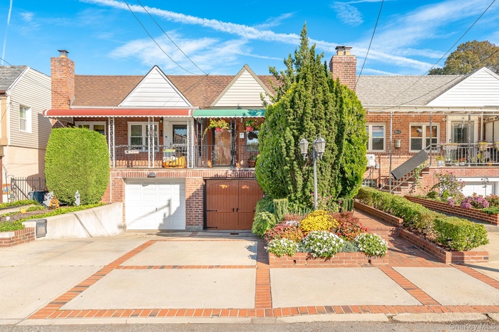 View of front facade featuring a chimney, concrete driveway, roof with shingles, brick siding, and an attached garage